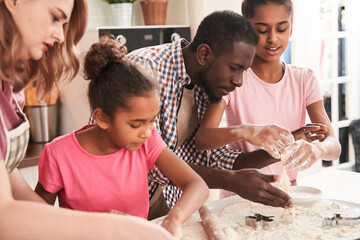 Fototapeta premium Parents showing professional way of cooking to curious little daughters