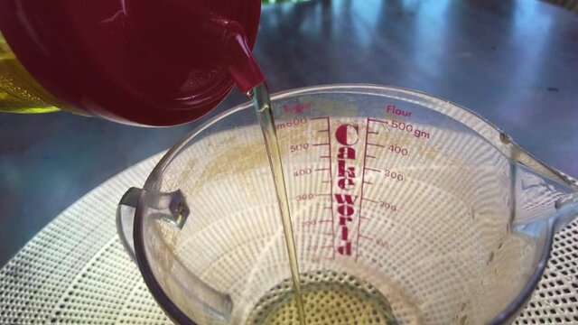 Pouring Vegetable Oil Into The Measuring Cup With Cake World Word.