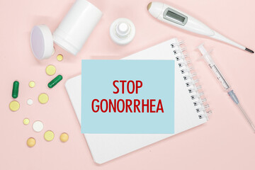 Notebook page with text Stop Gonorrhea on a table, pills and syringe. Medical concept.