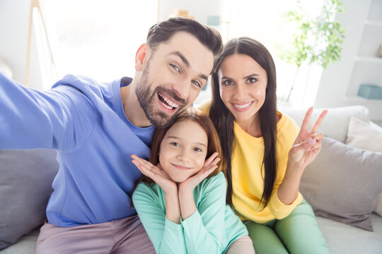 Photo of cheerful young family mom dad daughter happy positive smile show peace cool v-sign sit sofa home