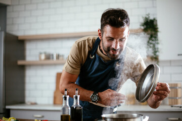 Handsome man preparing pasta in the kitchen. Guy cooking a tasty meal.