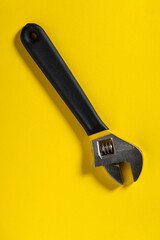 Adjustable wrench on a yellow background. Necessary tool of plumbing master or builder