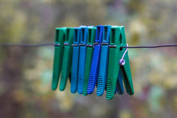 clothespins hanging with wire on​ green​ blur​ background. Old clothespins hang on the wire outdoor, blurred background, selective focus.colorful clothespins hang on a wire 