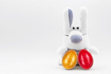 White Easter bunny with painted eggs on a white background. Soft toy rabbit for Easter. Easter holiday concept. Copy space. Mock up