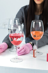 The girl is dripping pigments into glasses. Dissolving the pigment in water. Tube with the inscription: Pigments, Lips.