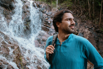 Male tourist near a small mountain tropical lake and waterfall.