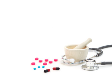 Hospital, clinic, healthcare and medical concept. Stethoscope, Mortar and Pestal with capsule, pink and blue pills isolated on white background. Mortar and Stethoscope using as pharmacy concept.