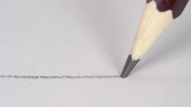Artist hand drawing a flat gray line with a graphite wooden pencil on white paper. Close up, macro, 4k