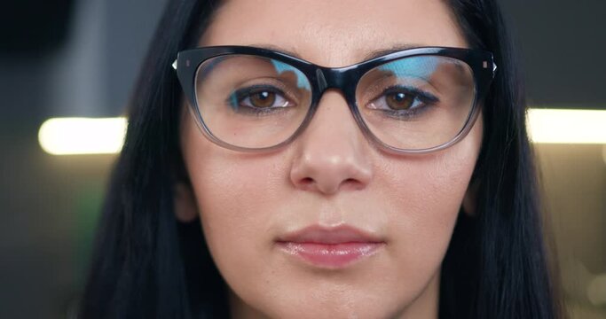 Front view of lovely positive successful dark-haired adult woman which wearing stylish glasses and looking at camera with confident face
