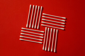 cotton buds on a red paper background. White cotton swabs. Health. Ear cleaner. Medical hygiene products. Cotton pads. Ear cleaning wallpaper. Top view of the pile of ear sticks.
