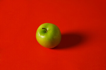 Perfect Fresh Green Apple Isolated on red background as pack design element. Whole green apple with lighting from the right side. Green apple wallpaper. Vitamin fruit is very suitable as a juice drink