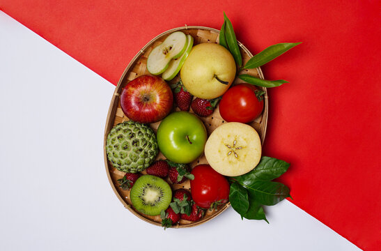 Assorted fruit, randomly arranged, isolated on red and white background. Fresh fruit is very good as a substitute for staple food while doing the diet process. Fruit wallpaper. Top view.