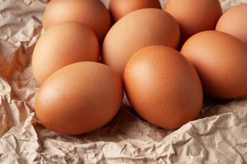 Group of brown eggs. Close-up of raw brown chicken eggs on crumpled wrapping paper. High calorie protein food concept.