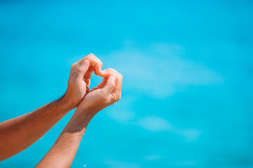 Fototapeta premium Female hands in the form of heart against the turquoise sea