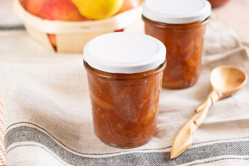 Homemade apple jam marmalade with cloves and cinnamon from organic apples in a transparent glass near wooden spoon. Homemade autumn jam confiture preserves.