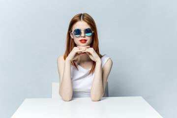 pretty red-haired woman wearing sunglasses red lips light background