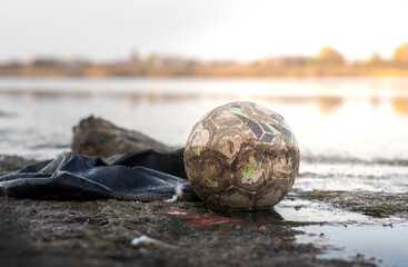 Old ball in the water. Pollution with household waste on Lake Pomorie near Burgas, Bulgaria. Imprint of human activity on nature.
