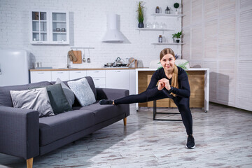 Young beautiful sports girl in leggings and a top does exercises at home on the couch. Healthy lifestyle. The woman goes in for sports at home.