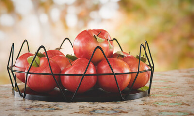Red apples in a metal fruit basket on a garden background. 3d render