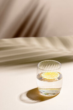 Glass Of Water With Lemon  On Beige Background With Hard Light And Shadow