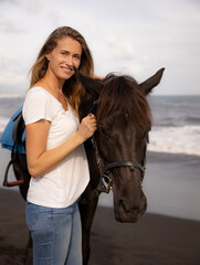 Fototapeta premium Portrait of happy woman and brown horse. Caucasian woman hugging horse. Romantic concept. Love to animals. Nature concept. Bali