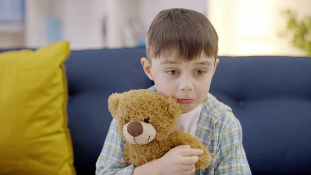 Sad child hugging teddy bear toy, negative emotions, bad memories, problem