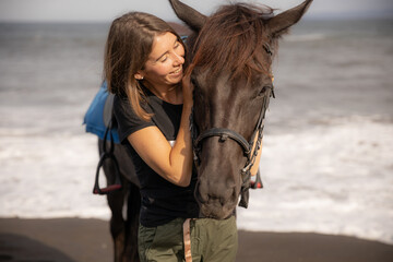 Fototapeta premium Portrait of smiling woman and brown horse. Young Caucasian woman hugging horse. Romantic concept. Love to animals. Nature concept. Bali