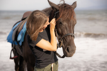Obraz premium Portrait of young woman and brown horse. Young Caucasian woman hugging horse. Romantic concept. Love to animals. Nature concept. Bali