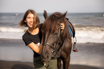 Portrait of happy woman and brown horse. Young Caucasian woman hugging horse. Romantic concept. Love to animals. Nature concept. Bali