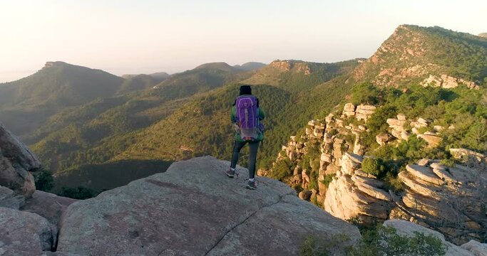 Mujer aventurera con mochila disfrutando de las vistas en la cima de una monta&ntilde;a