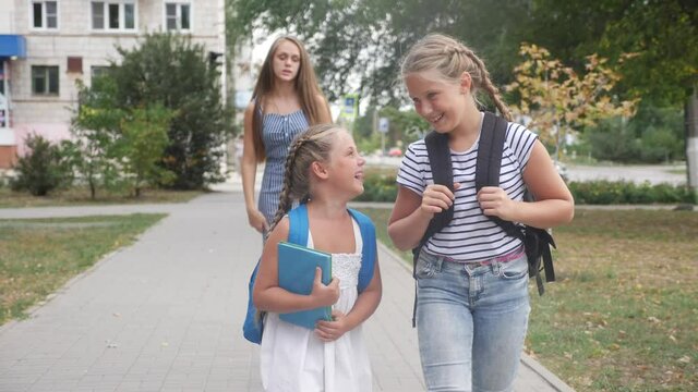group of schoolchildren walking to school along the path. happy family school concept.little schoolgirl with backpack and textbook. schoolgirls walk along in education the park school to for lessons