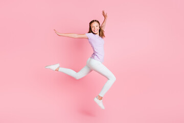 Fototapeta na wymiar Full body profile side photo of happy cheerful small girl jump up raise hands isolated on pink color background