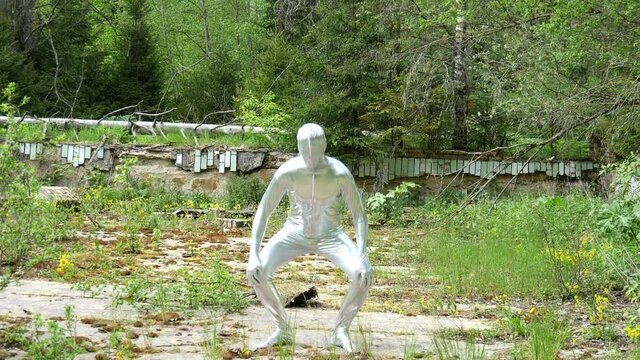 Tall slender man in silver suit is fully dressed in tight silver suit, dancing slowly at bottom of an abandoned pool in summer. Unusual freak dances. An alien, wonderful unusual person, UFO. Tin man