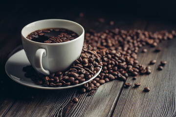 fragrant coffee beans on a wooden table and a cup with a hot drink on a saucer