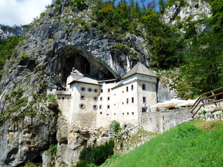 Fototapeta na wymiar Vista general del Castillo de Predjama (Eslovenia) incrustado en una roca a media altura de una montaña y sirviendo de entrada a una cueva