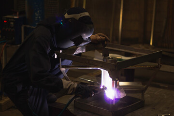 Welder is welding the steel in the factory.