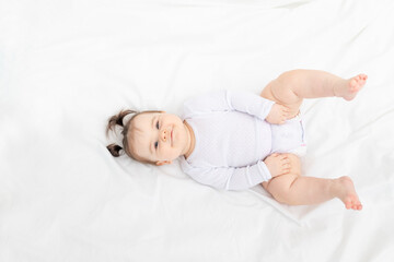 baby lying on the bed at home on a white bed, the concept of a happy loving family and children