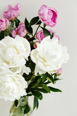 Simple sloopy flower bouquet of pink and white peonies flowers over pastel background
