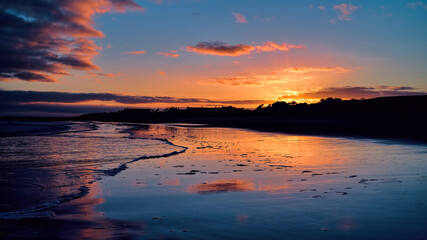 Fototapeta na wymiar Winter golden sunset on Brora beach in the Highlands with reflections in the wet sand