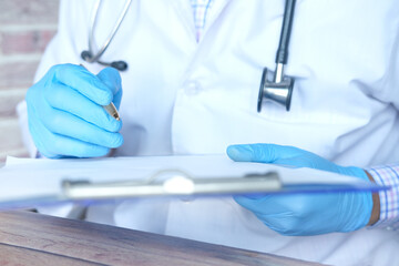 doctor hand in latex gloves writing prescription on desk, close up.