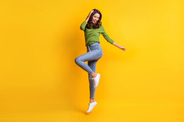Fototapeta na wymiar Full size photo of gorgeous active young woman wear jeans touch hair jump up isolated on vibrant yellow color background