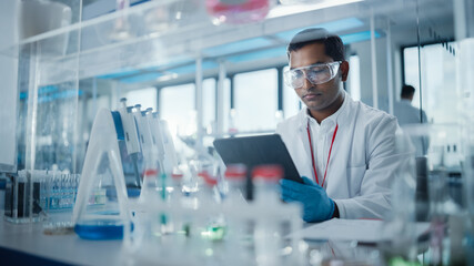 Medical Research Laboratory: Portrait of a Handsome Male Scientist Using Digital Tablet Computer to...