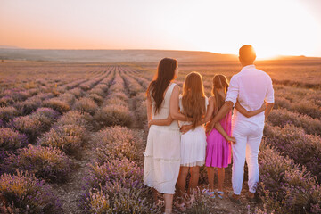 Family in lavender flowers field at sunset in white dress and hat