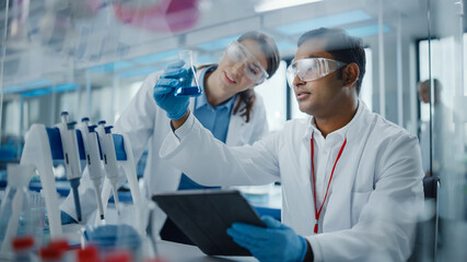 Modern Medical Research Laboratory: Two Scientists Working Together Analysing Chemicals in...