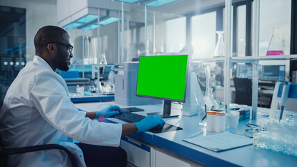 Naklejka premium Modern Medical Research Laboratory: Scientist working on Computer Showing Green Chroma Key Screen. Scientific Lab, Medicine Development Facility with Advanced Equipment, Biotechnology.