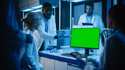 Medical Research Laboratory Meeting: Diverse Team of Scientists Use Computer Showing Green Chroma Key Screen, Discuss Innovations. Advanced Lab for Medicine, Vaccine Development. Blue Evening Shot