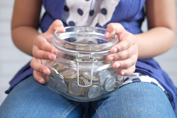 child girl holding jar of coins close up 