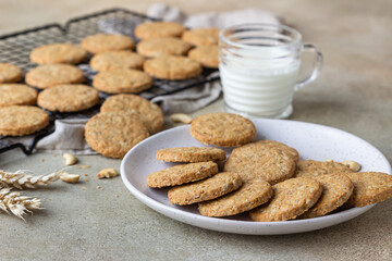 Healthy oatmeal cookies with cereals, seeds and nuts with a cup of milk on concrete background. Diet vegan cookies.