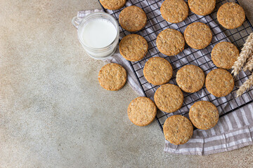 Healthy oatmeal cookies with cereals, seeds and nuts with a cup of milk on concrete background. Diet vegan cookies. Top view.