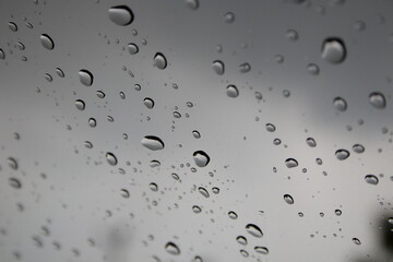 Drops of rain on windshield and blur clody sky background.